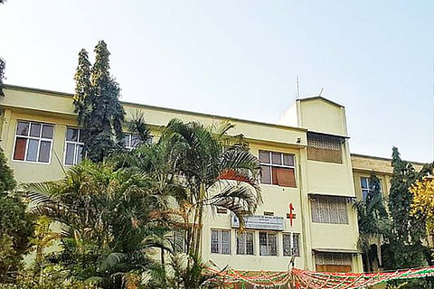 A pale green building in the TISS Hyderabad campus with trees in the foreground