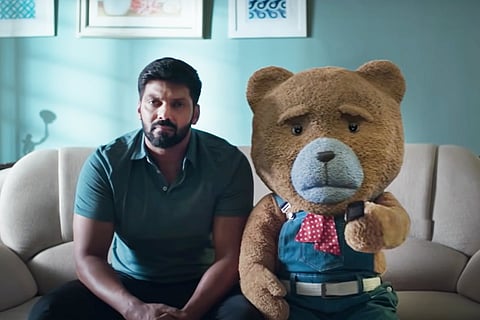 Arya and brown teddy bear from Teddy sitting on a beige couch