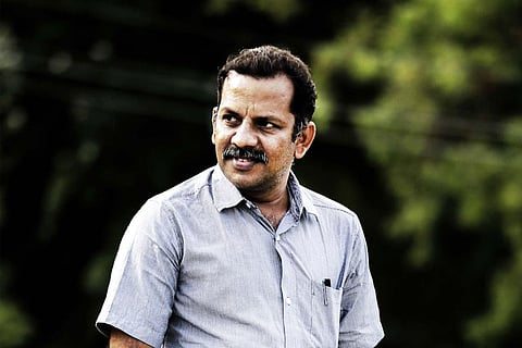 Director Thamira in pale blue shirt looking to the side