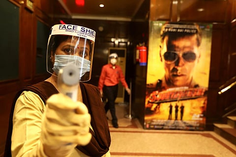 Workers wear facemasks and face shields inside a theatre during a sanitisation work ahead of the scheduled reopening of cinema theatres