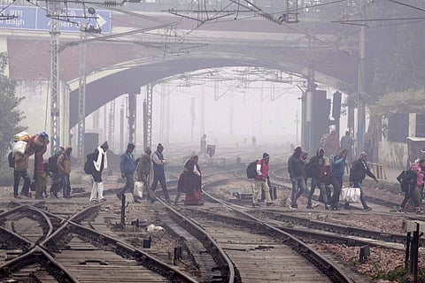 People crossing railway tracks amidst fog