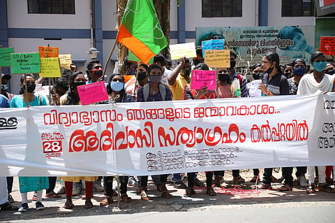 Kerala tribal students protest in street holding a banner for right to higher education