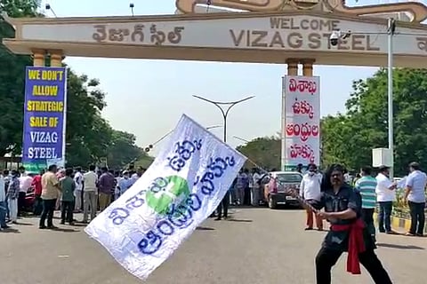 A man waving a flag outside the Vizag Steel Plant