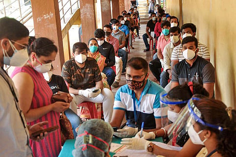 People seated in line waiting for vaccination