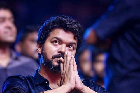 Vijay wearing a black shirt and with his hands folded