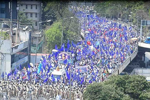 A sea of protesters with blue flags making their way on the Race Course Road flyover in Bengaluru