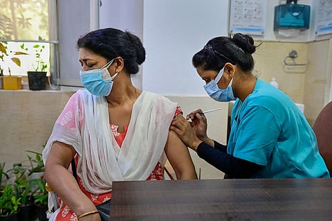A health worker inoculates a woman with a booster dose against COVID-19