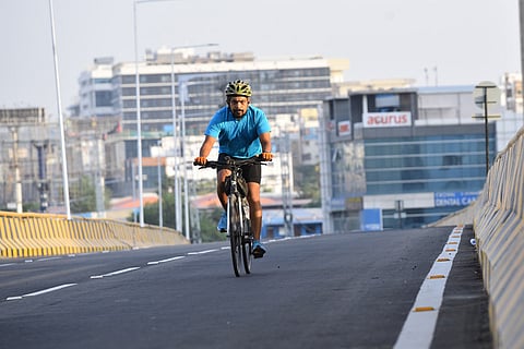 A man wearing an helmet riding a cycle on a deserted flyover