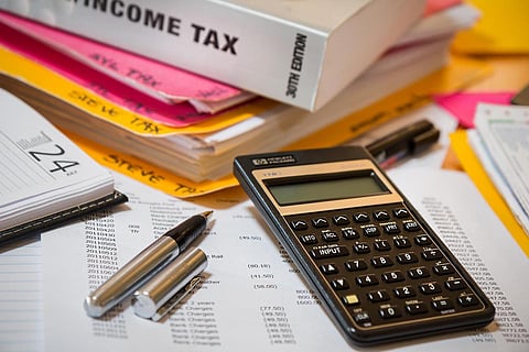Income tax return filing deadline: Representative image of a calculator and a pen and documents on a table