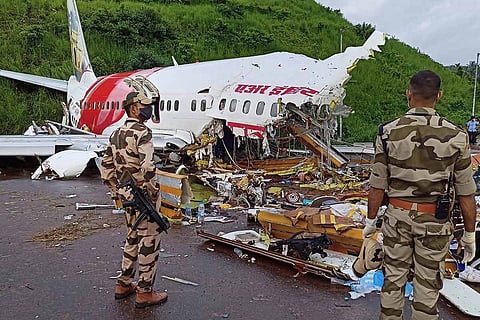 Two security personnel stand before the wreckage of the Dubai-Kozhikode Air India Express flight that crashed at Karipur airport on August 7, 2020