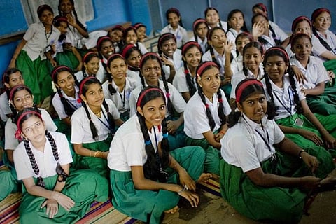 A classroom of girl students in green skirts and white shirts