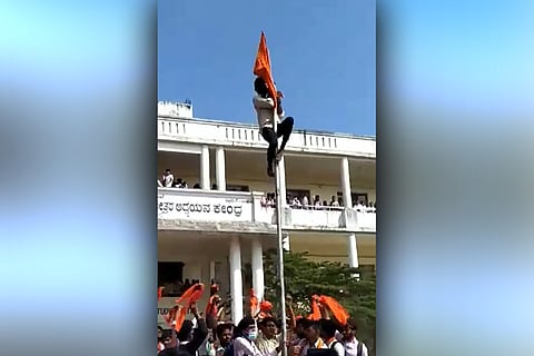 A person seen hoisting the saffron flag in a Shivamogga college as others cheer him on
