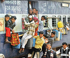 Passengers hang on to a running local passenger train in Patna on Friday.