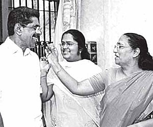 Usha Ramachandran giving sweets to Mullappally as daughter Parvathy looks on in New Delhi on Wednesday.