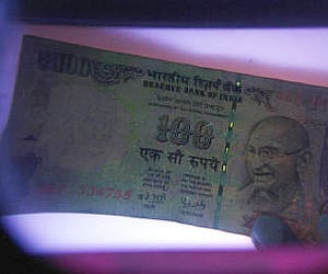 A man uses an electronic machine to check a currency note at a money exchange shop in Siliguri in this May 18, 2009 (File photo/Reuters)