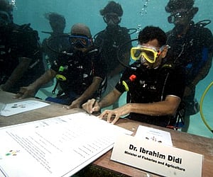 Maldivian Minister of Fisheries & Agriculture Ibrahim Didi signs a document calling on all countries to cut down their carbon dioxide emissions. (AP)