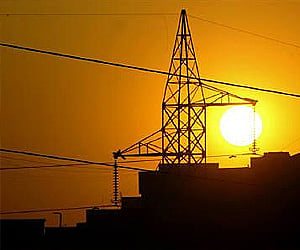 Sun sets behind a power tower near a building in New Delhi. (Photo: Reuters)