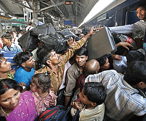Passengers struggle to enter the Patna-bound 2393 Up Sampoorna Kranti Express train at the New Delhi Railway Station in New Delhi on Sunday.