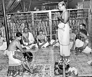 A girl devotee placing gold on the astrological frame to mark the beginning of the Ashtamangala Thamboola Prasnam.