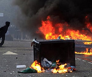 A masked youth pulls a burning garbage bin set on fire by rioters in Hackney, east London during London riots. (File photo: AP)