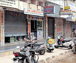 (Top) Shops at Musheerabad functioning with half-closed shutters during the Telangana bandh on Friday and (below) RTC bus drivers sleeping atop a bus