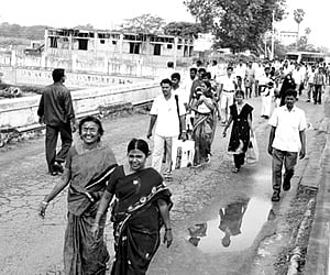 Passengers alight from buses at one end of the Thirumalairajanar bridge and cross it on foot, following damage to the bridge.