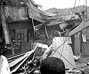 An earth mover tears into shops illegally erected along the Girivalam path near the Sree Arunachaleswarar Temple in Tiruvannamalai, Sunday.