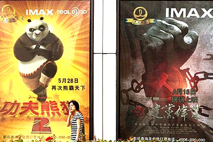 A woman walks past movie posters of Hollywood movies 'Kung Fu Panda 2', left, and China's propaganda film 'Beginning of the Great Revival' on display side by side outside a cinema in Beijing (AP Photo/Andy Wong).