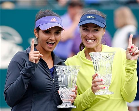 Sania Mirza (left) and her teammate, Martina Hingis, of Switzerland, hold their trophies after defeating Alla Kudryavtseva and Anastasia Pavlyuchenkova during a doubles final match at the Family Circle Cup tennis tournament Sunday, April 12, 2015. (Photo/