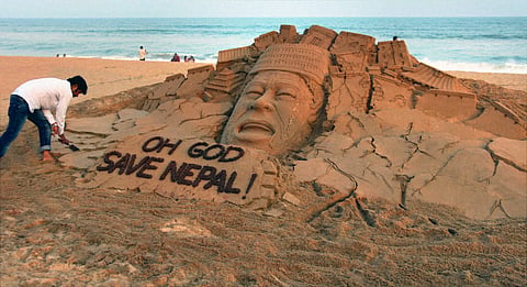 Puri Sand artist Sudarsan Pattnaik creates a sand sculpture on Nepal earthquake with a message "Oh God Save Nepal " at Puri beach of Odisha on Tuesday. (PTI)