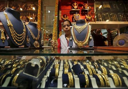 A saleswoman holds a pair of gold bangles while attending to customers at a jewellery showroom in Mumbai, July 21, 2015. | Reuters