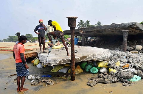 The concrete slabs of the century-old 'broken bridge' at Kozhikode beach being removed from the spot citing safety reasons. (A Sanesh | EPS)