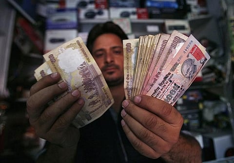 A shopkeeper poses for a picture as he counts money at his shop in Jammu. (File photo | Reuters)