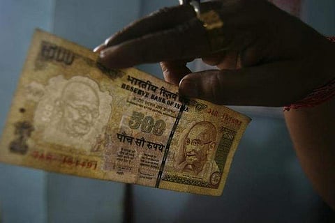 A man checks the now defunct 500 rupee note at a cash counter inside a bank in Agartala. (File Photo | Reuters)