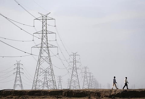 Men walk past electric pylons in Little Rann of Kutch in Gujarat March 2, 2014. REUTERS