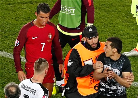 Portugal's Cristiano Ronaldo walks as a steward tries to block a man who invaded the pitch asking to take a selfie with him at the end of the Euro 2016 Group F soccer match between Portugal and Austria.(Photo| AP)