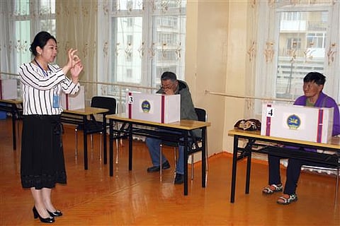 An election official explains the process of casting votes for residents at a polling station in Bayanzurkh district of Ulaanbaatar, Mongolia on Wednesday, June 29, 2016. (AP)