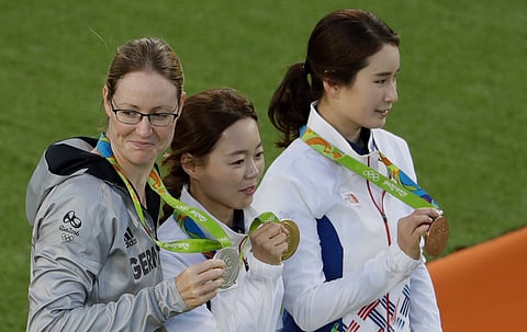 Gold medal winner South Korea's Chang Hye-jin, center, silver medalist Lisa Unruh, left, of Germany, and bronze medalist Ki Bo-bae, of South Korea, pose for pictures at the awards ceremony of the women's individual archery competition at the Sambadrome 