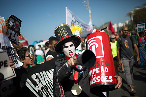 A demonstrator in a costume depicting a banker and holding a replica of a fire extinguisher for putting out the "flame" of an imitation Olympic torch, takes part in a protest against the interim Brazilian president Michel Temer, and the Rio's 2016 Summ