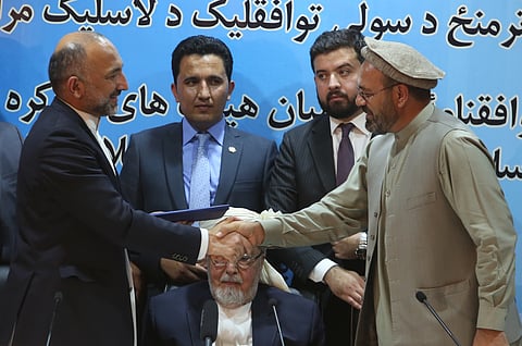 Afghanistan national security adviser Mohammad Hanif Atmar, left, and Amin Karim, representative of Gulbuddin Hekmatyar, right, shake hands after signing a peace deal in Kabul, Afghanistan. | AP