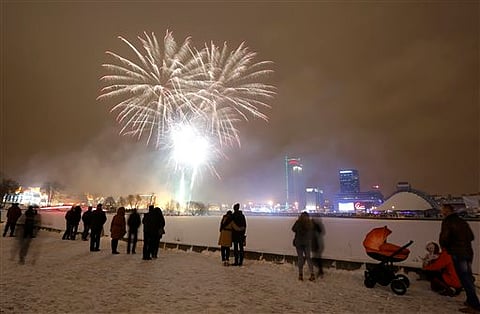 People watch fireworks explode over the ice covered Svisloch River during the New Year celebrations in Minsk, Belarus, Friday, Jan. 1, 2016. | AP