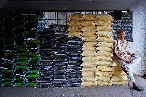 A labourer sits on sacks of food grains while waiting for customers at a wholesale market in Ahmedabad, December 14, 2016. | Reuters