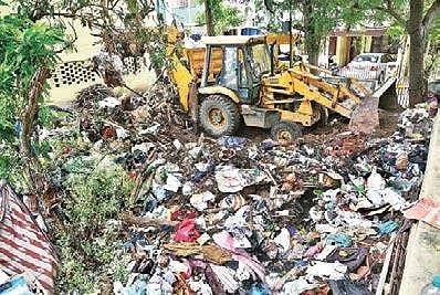 Corporation officials clear the waste from a single woman’s front yard in Jai Nagar, Koyambedu, using five mini tipper lorries and a front-loader. The woman is said to have collected the waste over a period of 12 years, in Chennai. | P Jawahar