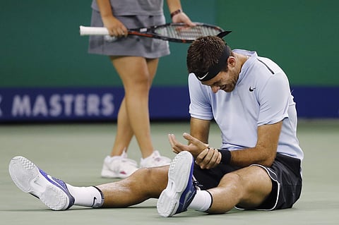 Juan Martin del Potro of Argentina holds his hand in pain after falling on the court during his men's singles quarterfinals match against Viktor Troicki of Serbia in the Shanghai Masters tennis tournament. | AP