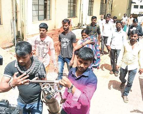 A woman carrying her sick child on her shoulder at KIMS in Hubballi. Her relatives    are seen carrying the oxygen cylinder