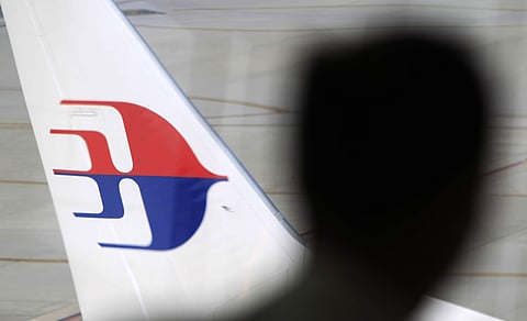 FILE - In this Sunday, March 9, 2014, file photo, a man looks out from a viewing gallery as a Malaysia Airlines aircraft sits on the tarmac at Kuala Lumpur International Airport in Sepang, Malaysia. | AP