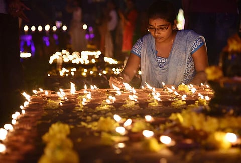 A woman lights an oil lamp to mark Koti Deepotsavam at NTR Grounds, in Hyderabad on Sunday. (R Satish Babu | EPS)