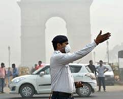 A traffic policeman wearing mask controls traffic amid smog in New Delhi. | PTI