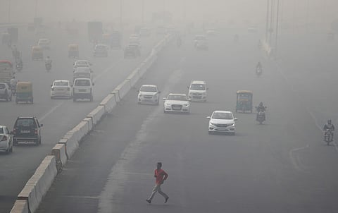 A man runs across an expressway cloaked in smog near Delhi, India November13, 2017. | Reuters