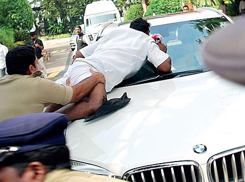 A policeman trying to restrain a KSU activist who blocked the car of Congress MP Vivek Tankha and waved black flags at him as the parliamentarian was on his way to the High Court on Tuesday | K Shijith